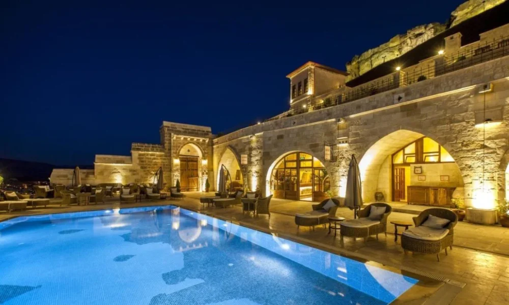 Illuminated stone hotel with pool at night