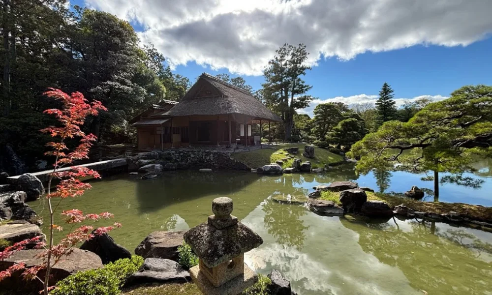 japanese garden with thatched house by pond