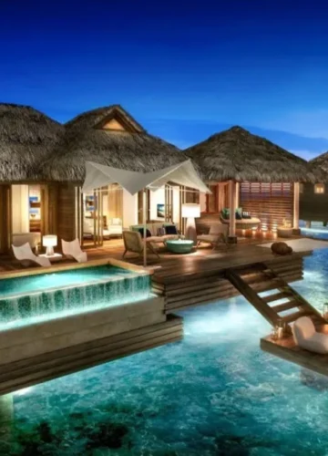 Overwater bungalows with thatched roofs at dusk