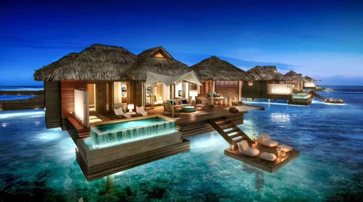Overwater bungalows with thatched roofs at dusk