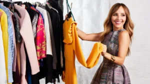 Smiling woman holding up a yellow dress from a clothing rack