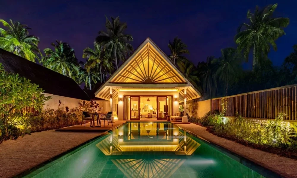 Tropical villa with pool at night, palm trees