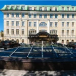 Grand hotel with green roof and cars parked outside