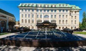Grand hotel with green roof and cars parked outside