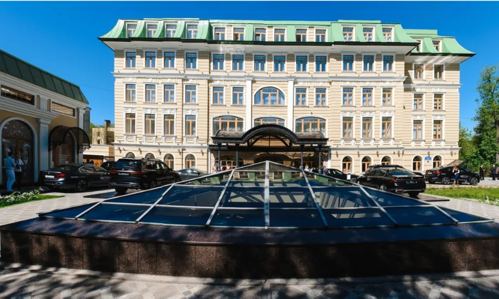 Grand hotel with green roof and cars parked outside