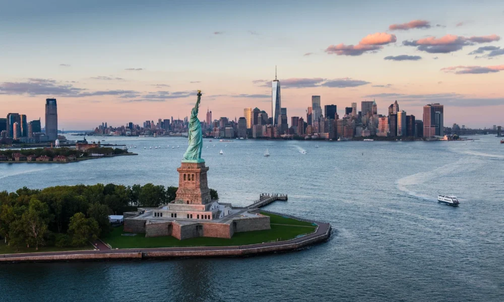 Statue of Liberty, NYC skyline at sunset