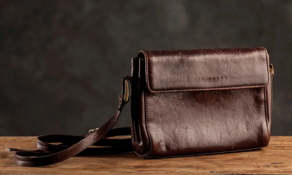 Brown leather shoulder bag on wood surface