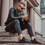Man in black leather jacket and jeans on steps