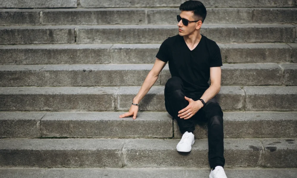 Man in black shirt and jeans on stone steps