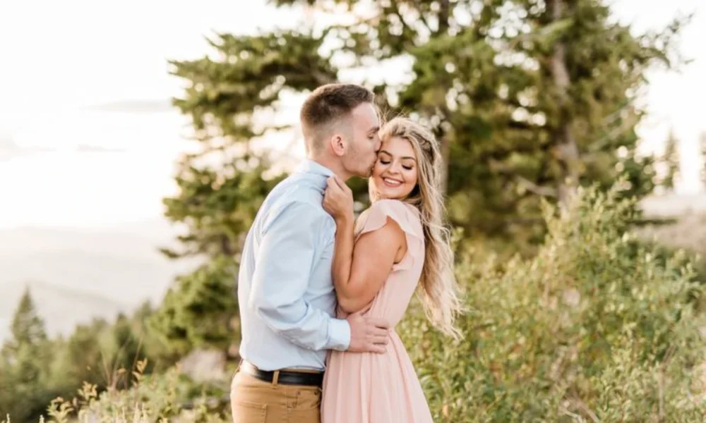 Man kissing woman's forehead in nature