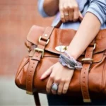 Person holding a brown leather satchel