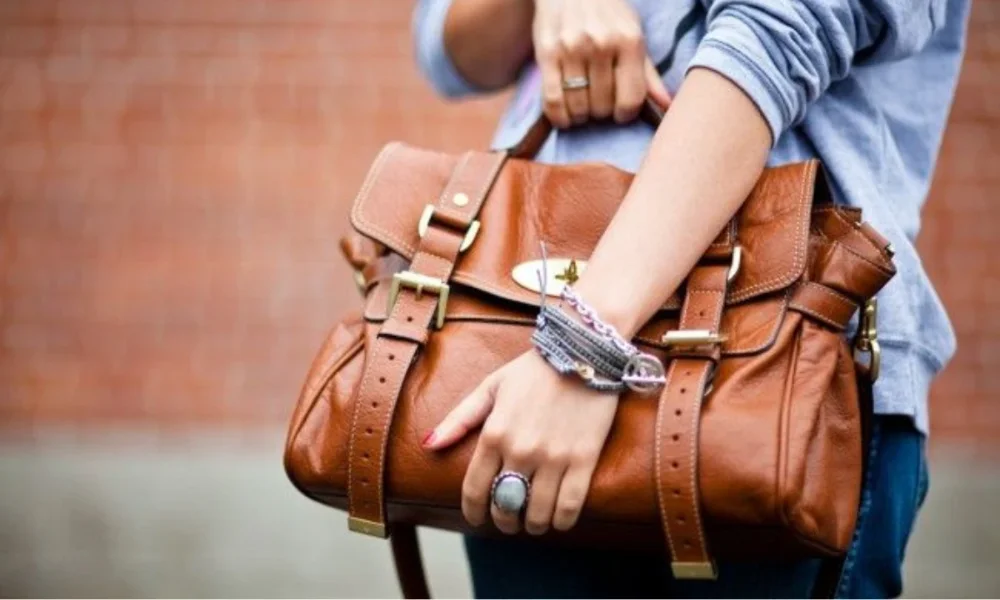 Person holding a brown leather satchel