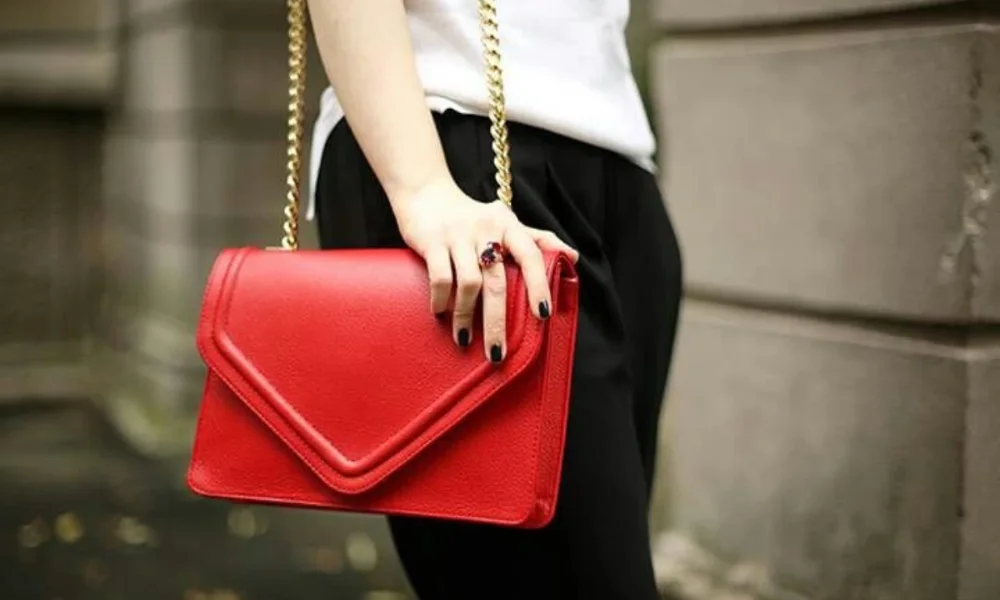 Person holding red leather clutch with gold chain