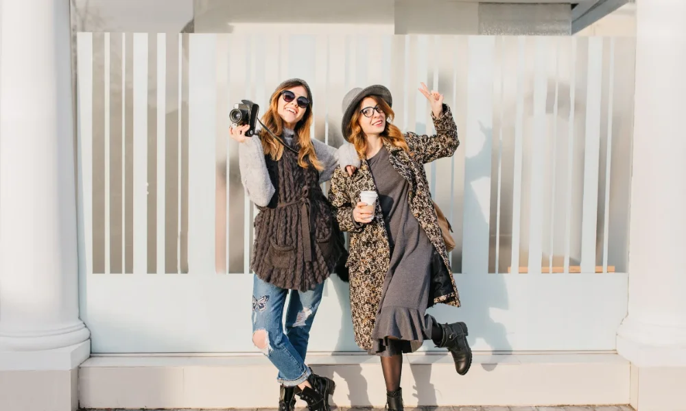 Two women posing, one with camera, one with coffee