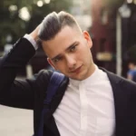 Young man in suit, hand on head, street