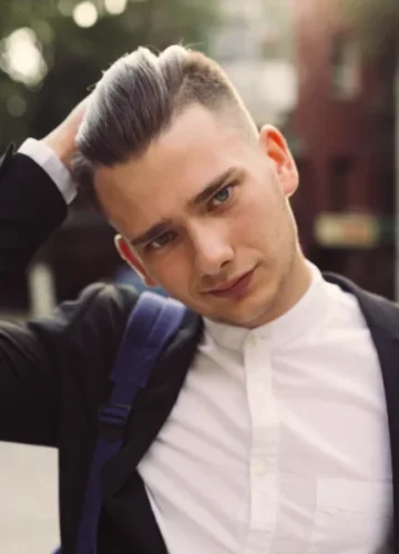 Young man in suit, hand on head, street