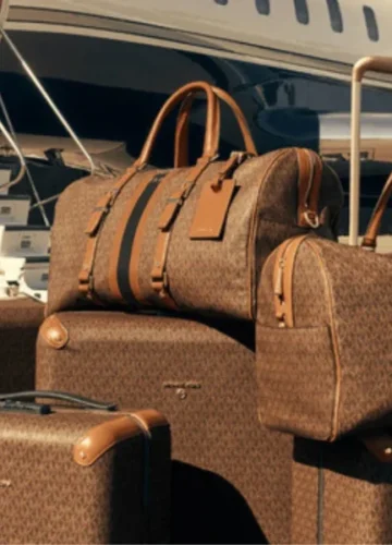 Brown Michael Kors luggage in front of a private jet