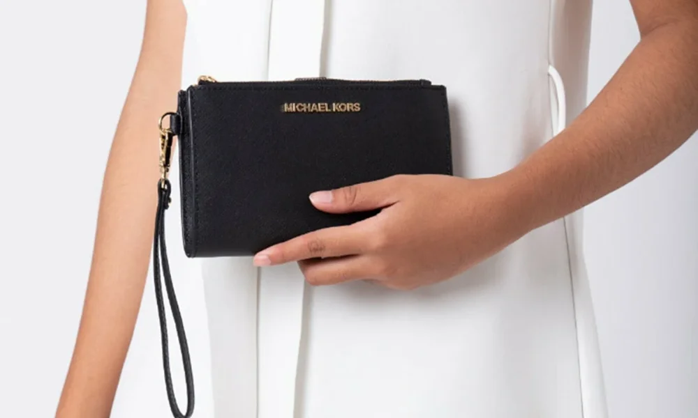 Hand holding black Michael Kors wristlet