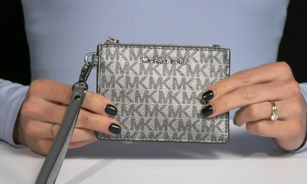 Hands holding silver Michael Kors wallet with strap