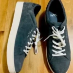 Pair of dark gray Michael Kors sneakers on wood