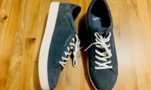 Pair of dark gray Michael Kors sneakers on wood