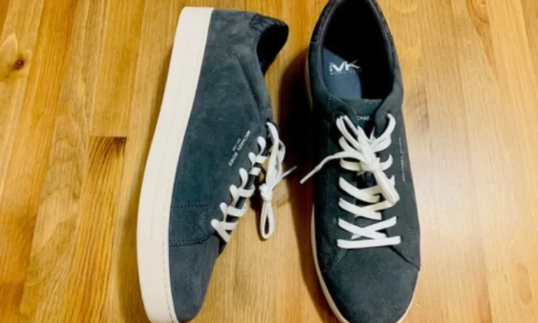 Pair of dark gray Michael Kors sneakers on wood