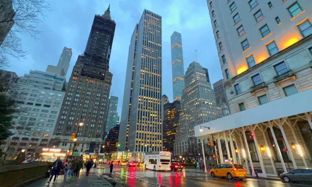 Rainy city street with tall buildings at dusk