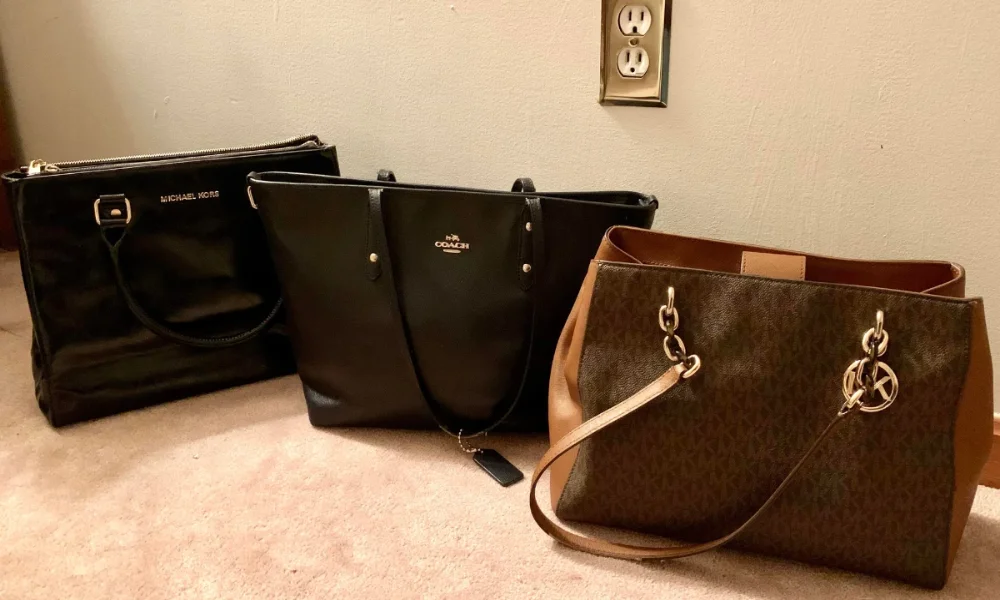 Three designer handbags on a carpeted floor 