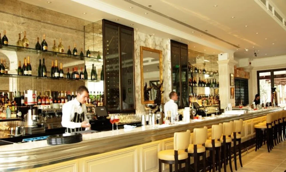 Elegant bar with two bartenders and many bottles