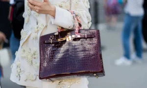 Person in embroidered jacket holding crocodile bag