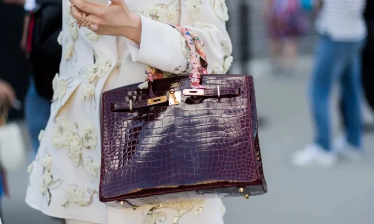 Person in embroidered jacket holding crocodile bag