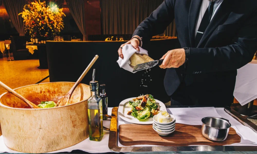 Waiter grating cheese over salad at table