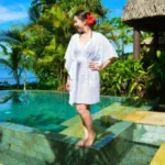 Woman in white kaftan by tropical pool