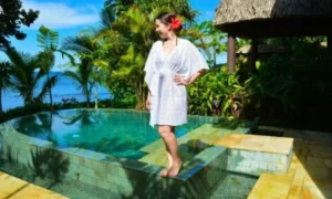 Woman in white kaftan by tropical pool