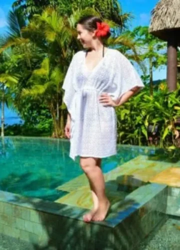 Woman in white kaftan by tropical pool