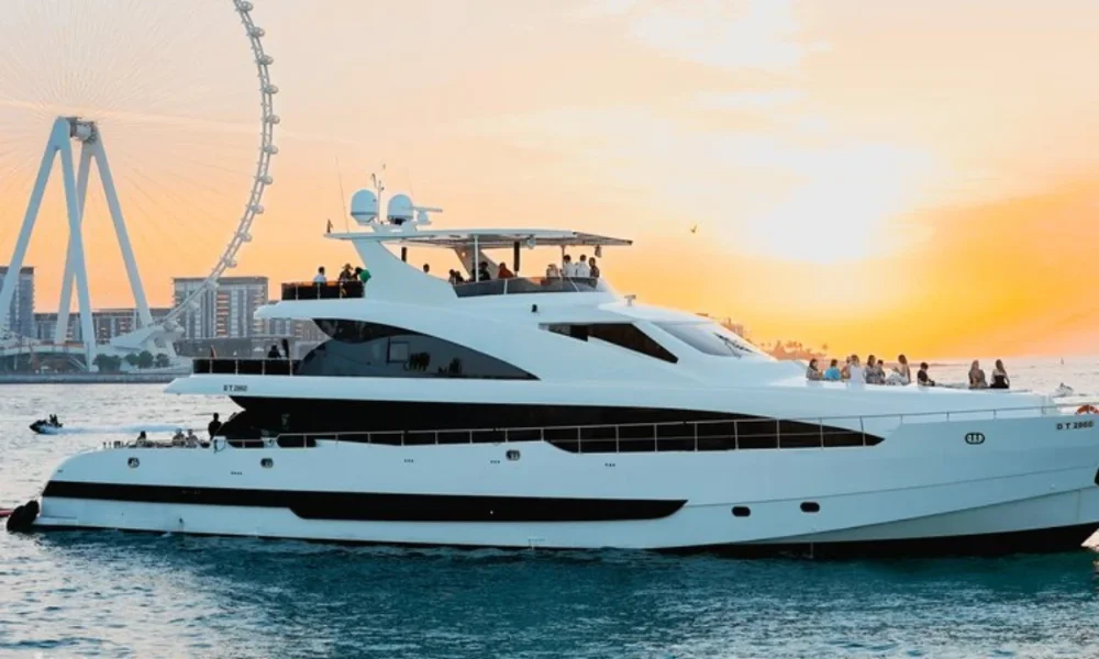 Yacht with people at sunset near Ferris wheel
