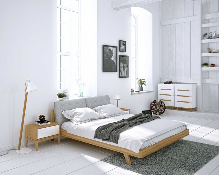 Minimalist Scandinavian bedroom setup featuring a low-profile wooden bed frame with light gray upholstered headboard and crisp white linen sheets