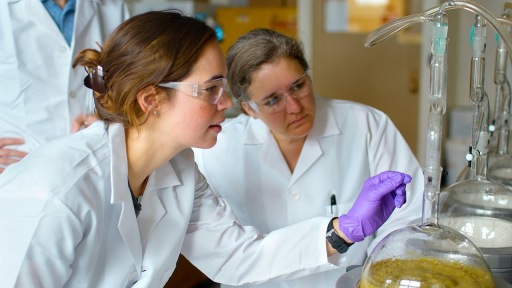Scientists in protective gear conducting experiments in a chemistry lab.