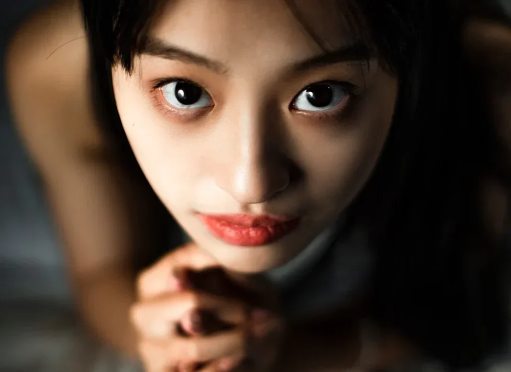 A close-up portrait of a person under dark red ambient lighting