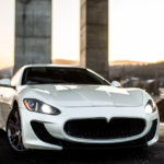White Maserati GranTurismo luxury sports car parked against modern concrete architecture at sunset