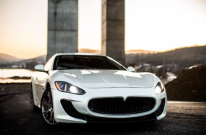 White Maserati GranTurismo luxury sports car parked against modern concrete architecture at sunset