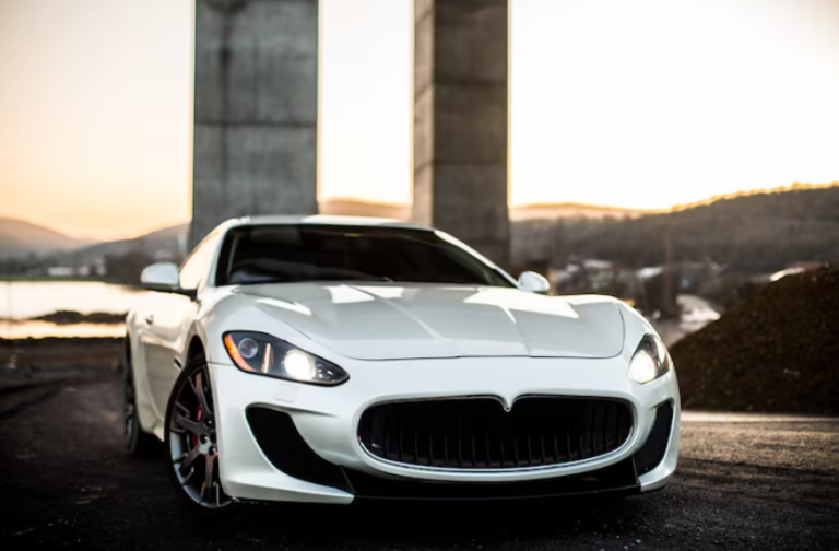 White Maserati GranTurismo luxury sports car parked against modern concrete architecture at sunset