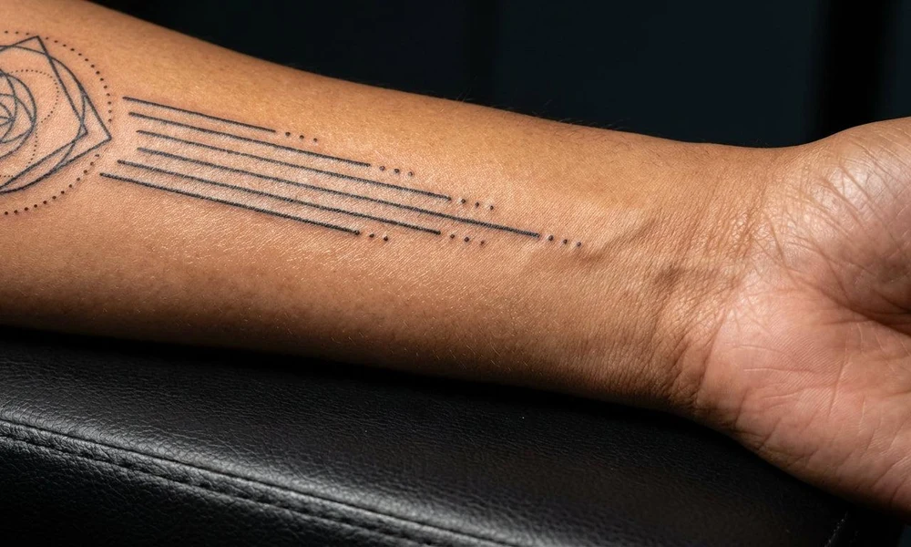 Fine-line geometric minimalist forearm tattoo on an inner arm.