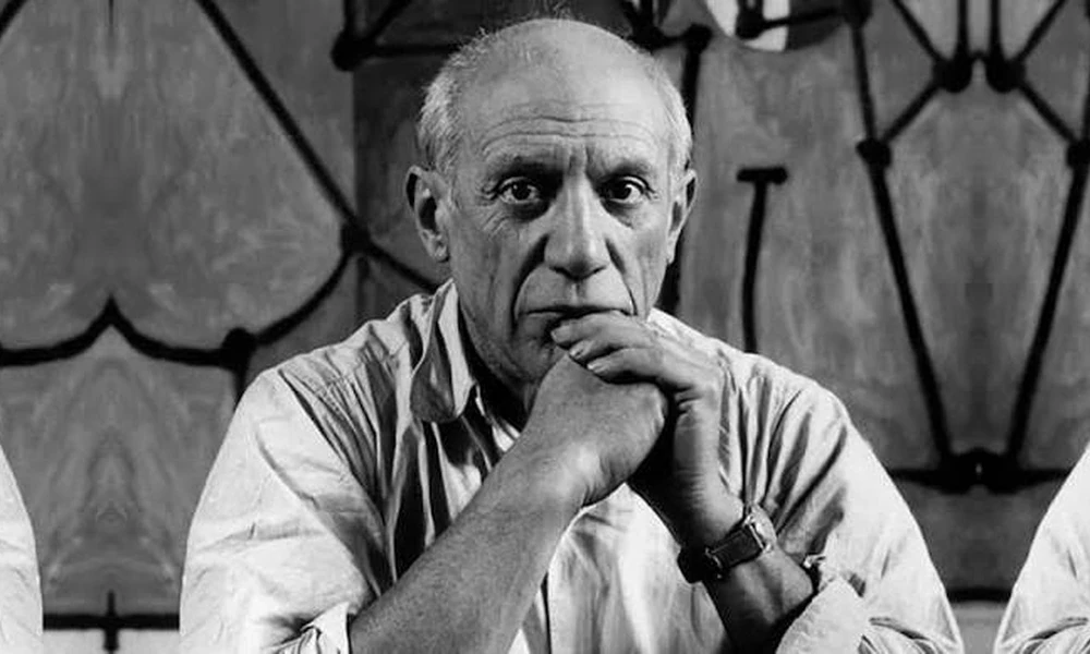 Black-and-white photo of modern artist Pablo Picasso (1881–1973) resting his chin on clasped hands