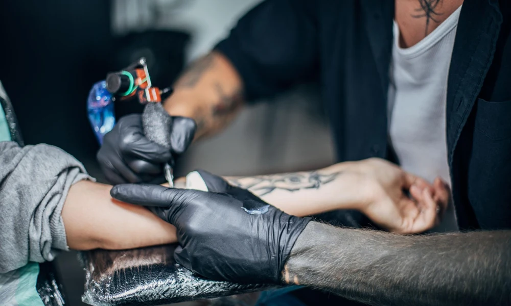 Professional tattoo artist working on a forearm tattoo.