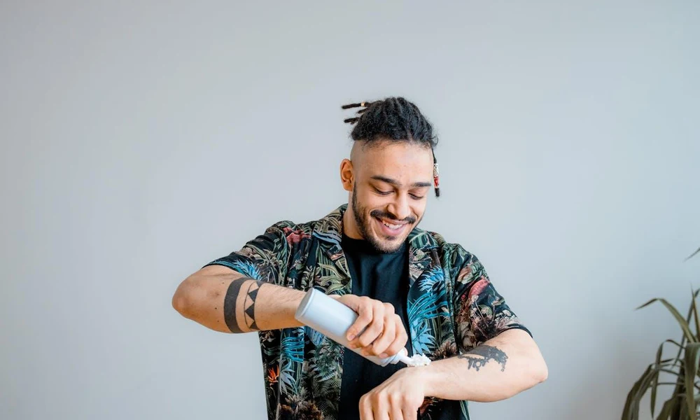 Man applying aftercare lotion to his healed forearm tattoo.