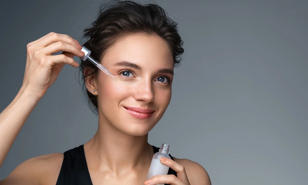 A woman applies facial serum with a glass dropper-Best Skin Care Products of 2026