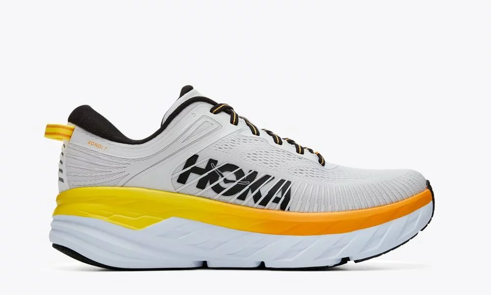 white HOKA running shoe with black laces, a yellow-to-orange midsole, and a thick white sole-Best Walking Shoes for Women