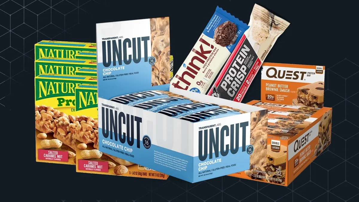 Assorted snack bars and protein treats from Nature Valley, Uncut, think!, and Quest arranged on a dark geometric backdrop in a bright product display.