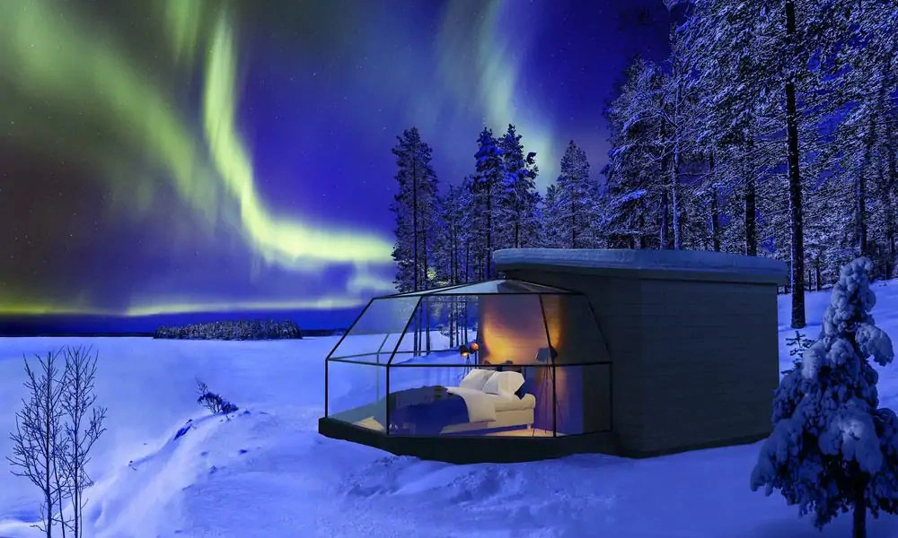 Green aurora borealis sweeps over a snowy Finnish forest and-Best Places to See the Northern Lights